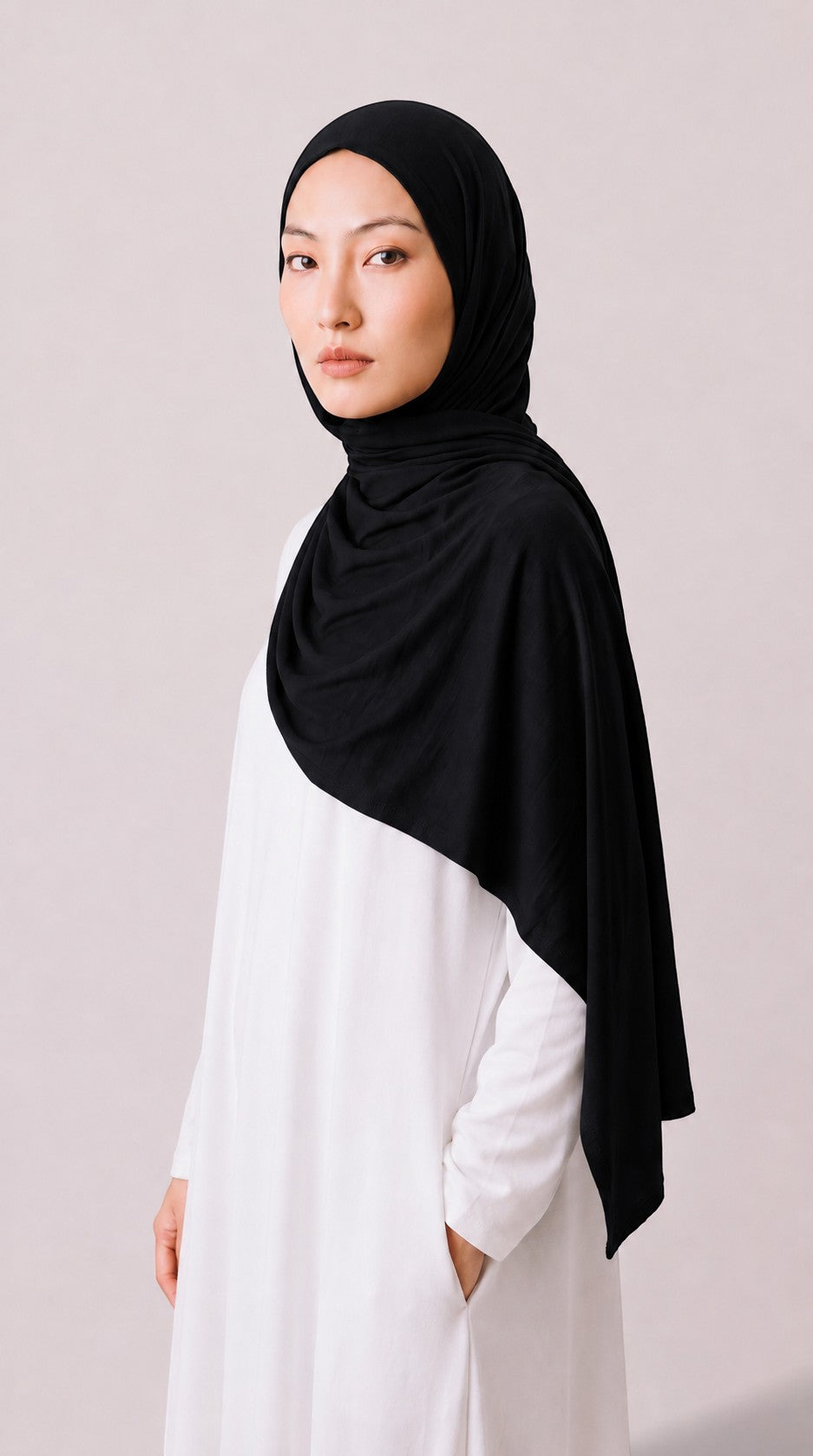 Eternal Aura black jersey hijab worn by a model in a white dress, featuring soft, stretchy, and lightweight fabric.