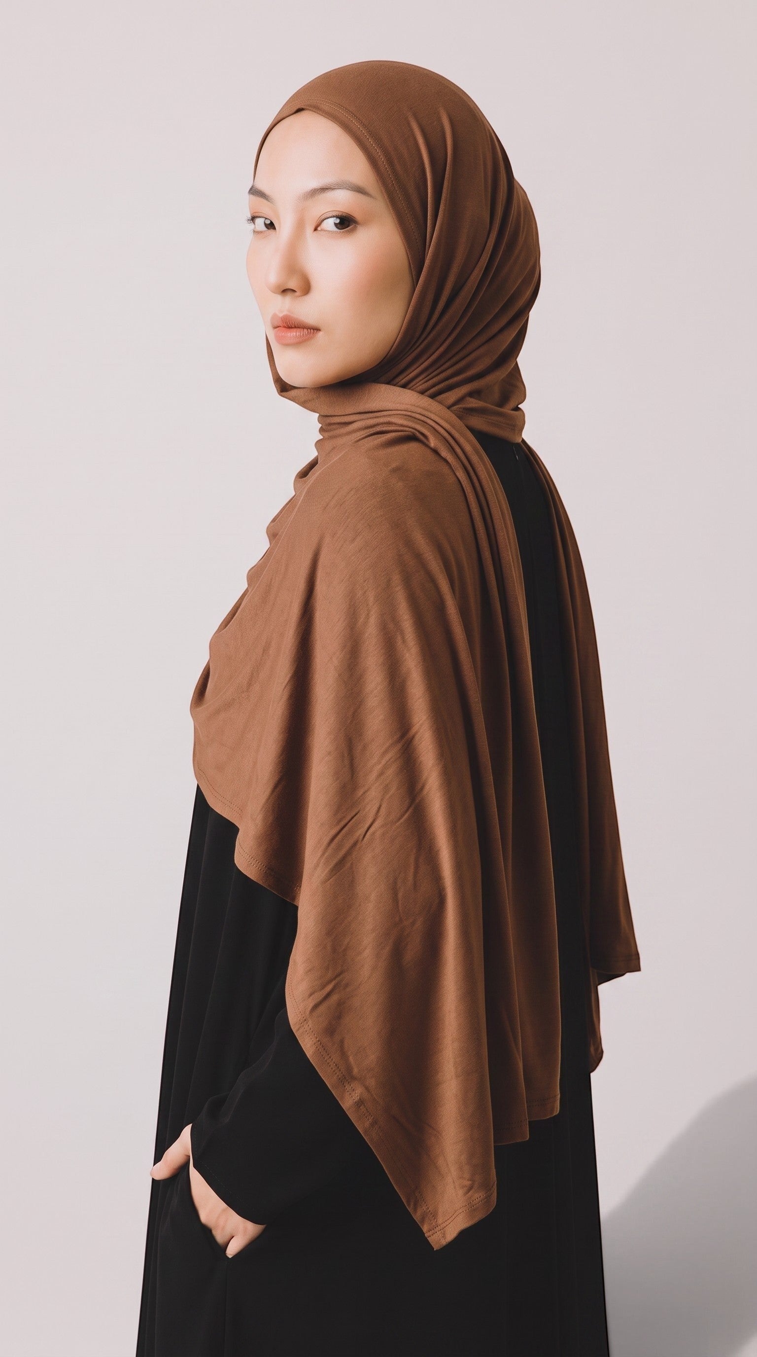 Model wearing a soft brown jersey hijab by Eternal Aura, featuring a lightweight and stretchy fabric drape.