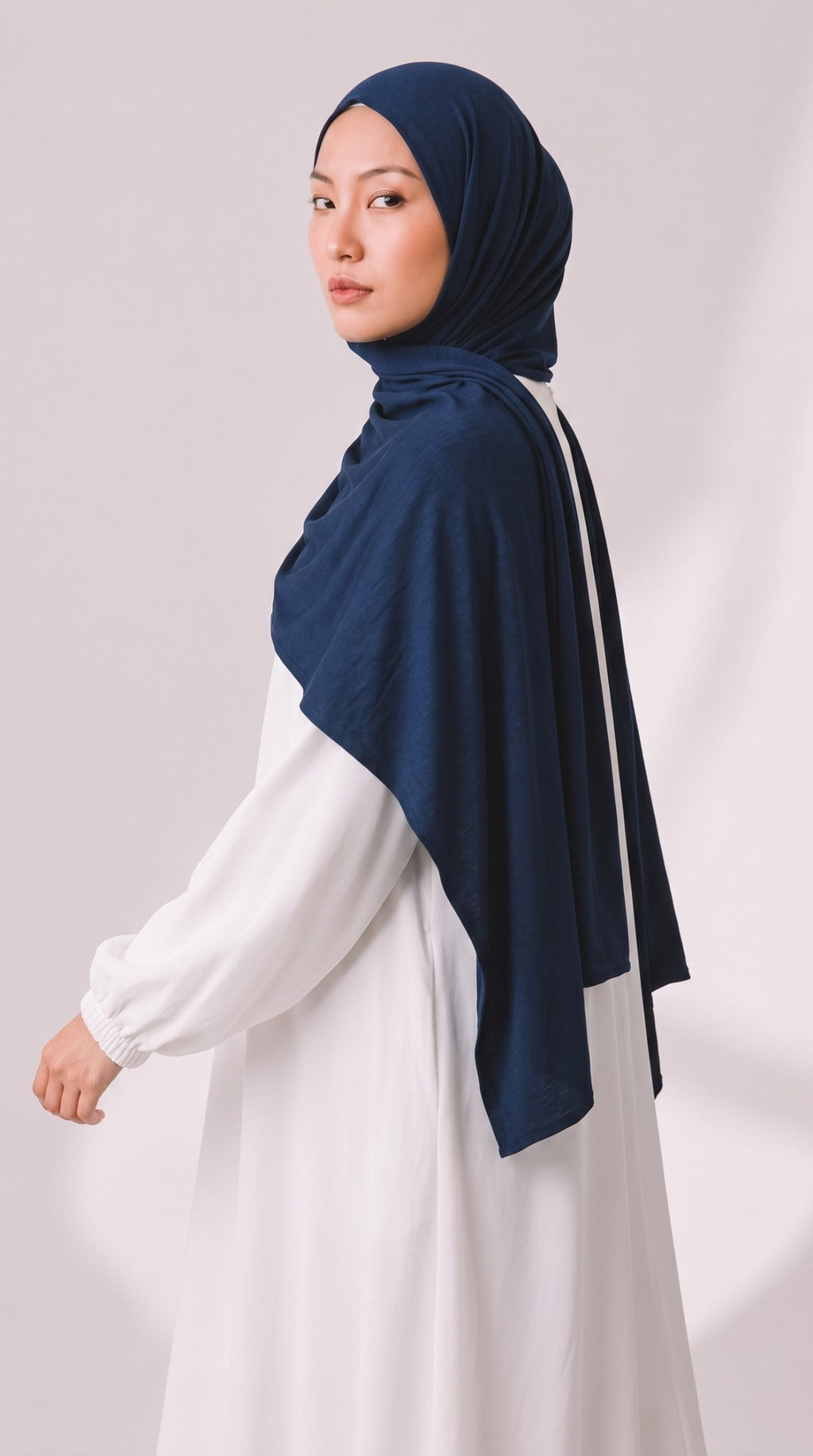 Eternal Aura Model trägt ein dunkelblaues Hijab aus weichem Stoff zu einem schlichten weißen Kleid