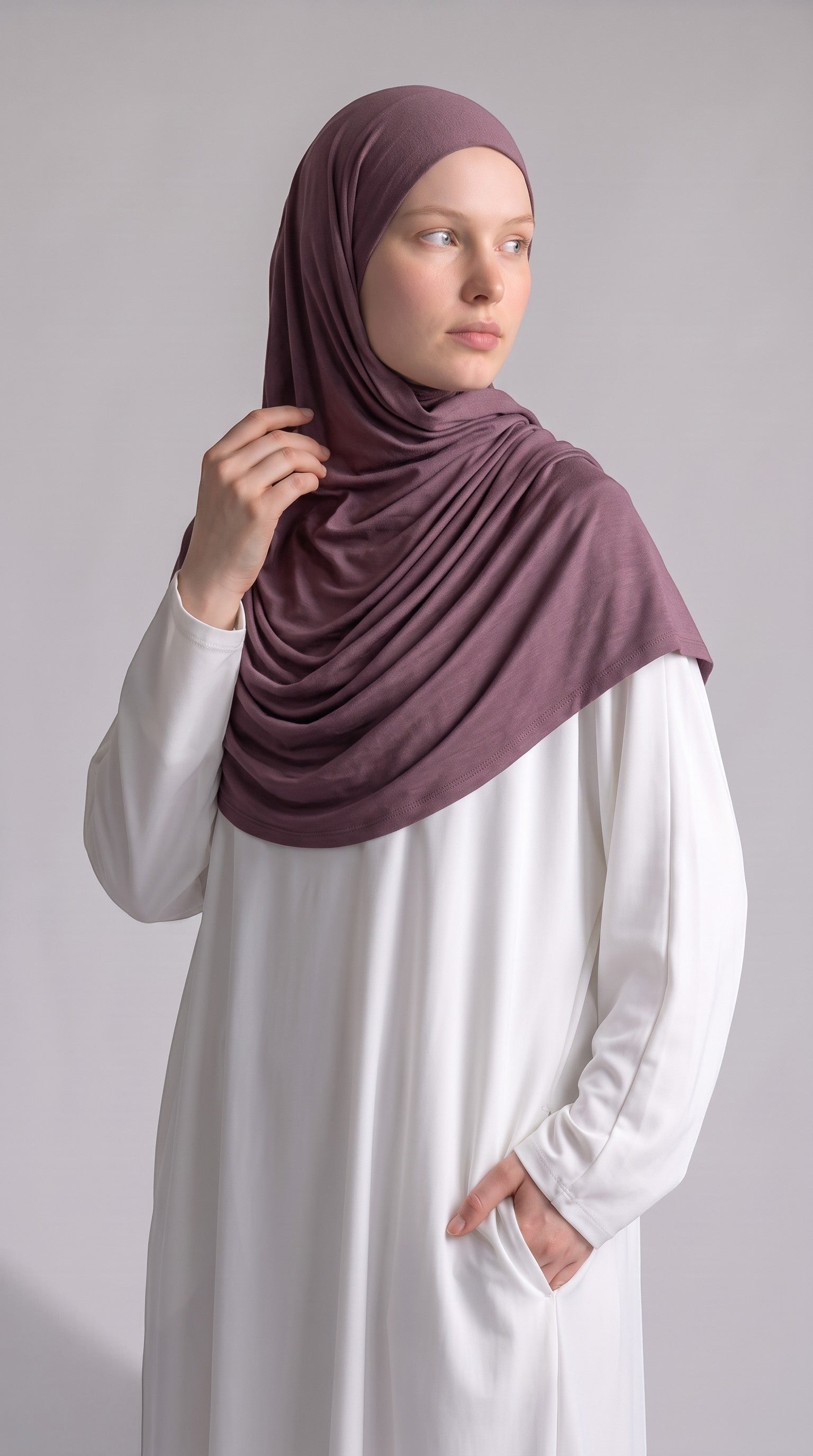 Model wearing a soft mauve Eternal Aura jersey hijab with a white long-sleeved dress against a neutral background