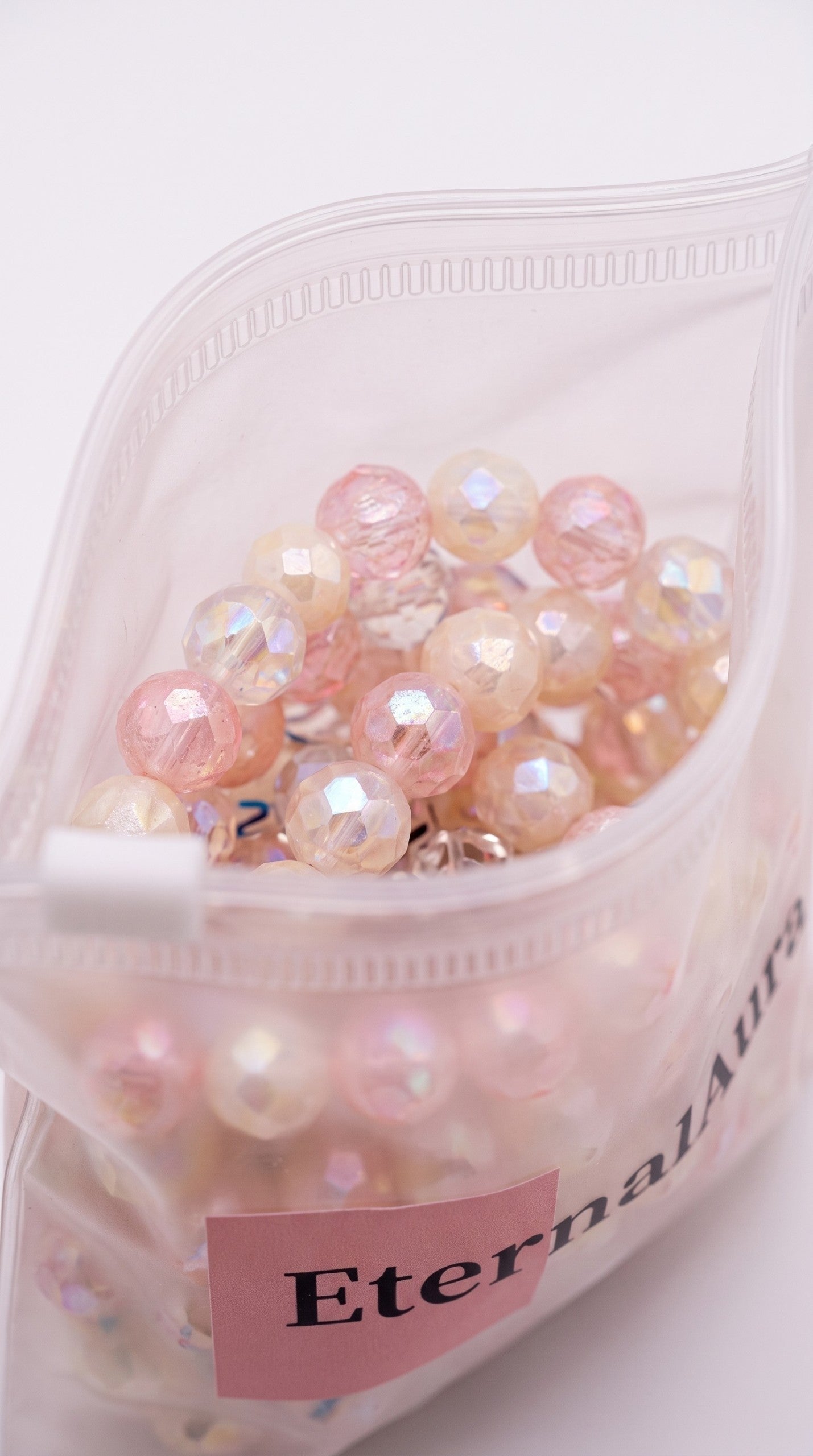 Eternal Aura Misbaha Gebetskette mit schimmernden rosa und cremefarbenen facettierten Perlen in einer Plastiktüte