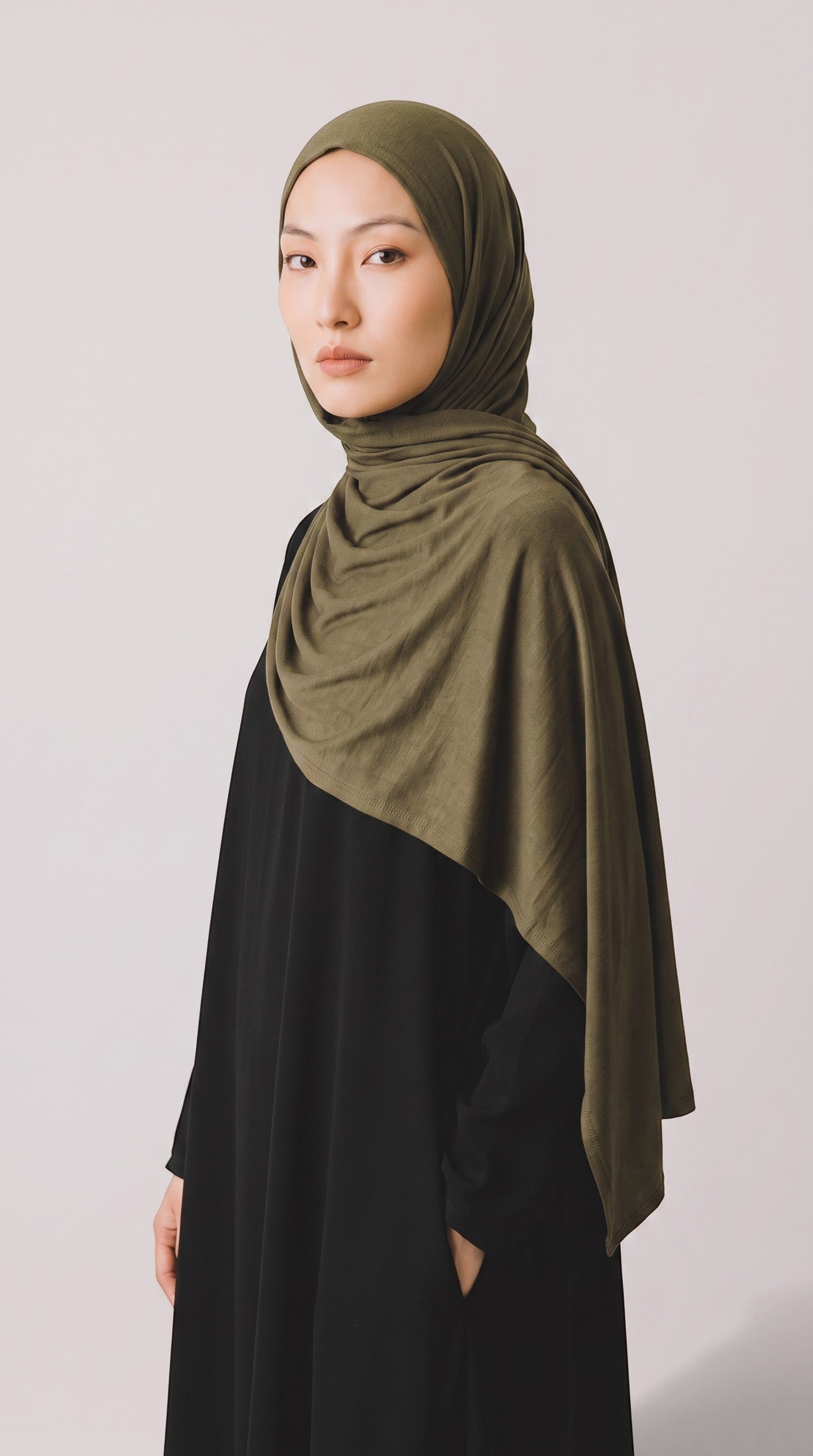 Eternal Aura olive green jersey hijab worn by a model, featuring a soft, stretchy, and lightweight fabric.
