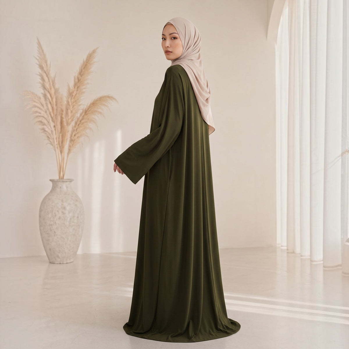 Eternal Aura The Serein Abaya in olivgrün mit weiten Ärmeln, getragen mit einem beigen Hijab in hellem Studio-Setting