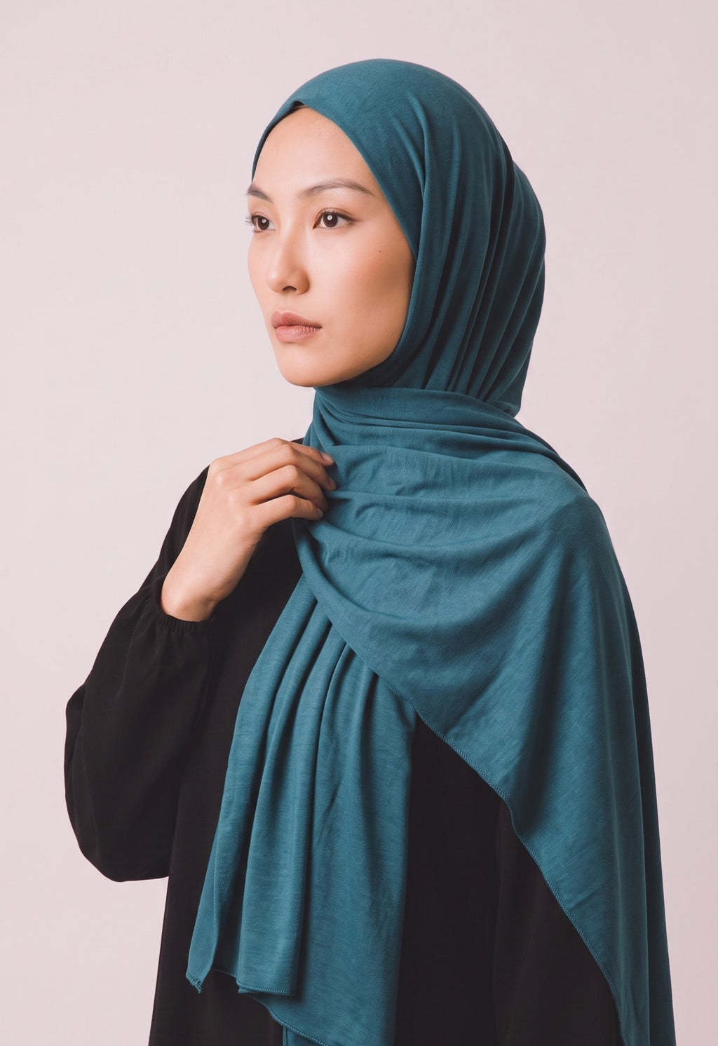 Model trägt ein petrolfarbenes Eternal Aura Jersey-Hijab aus weichem Stoff vor einem neutralen Hintergrund