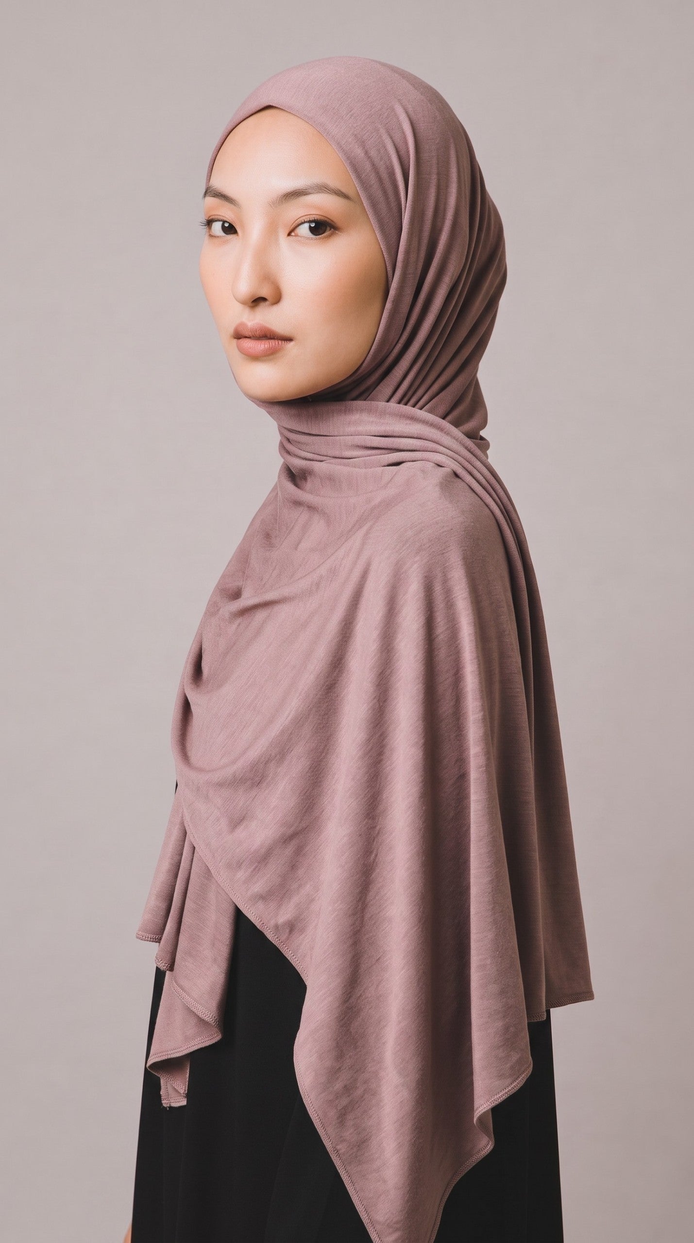 Model trägt ein staubiges rosa Eternal Aura Jersey-Hijab, das elegant drapiert ist und den Kopf und Hals bedeckt.