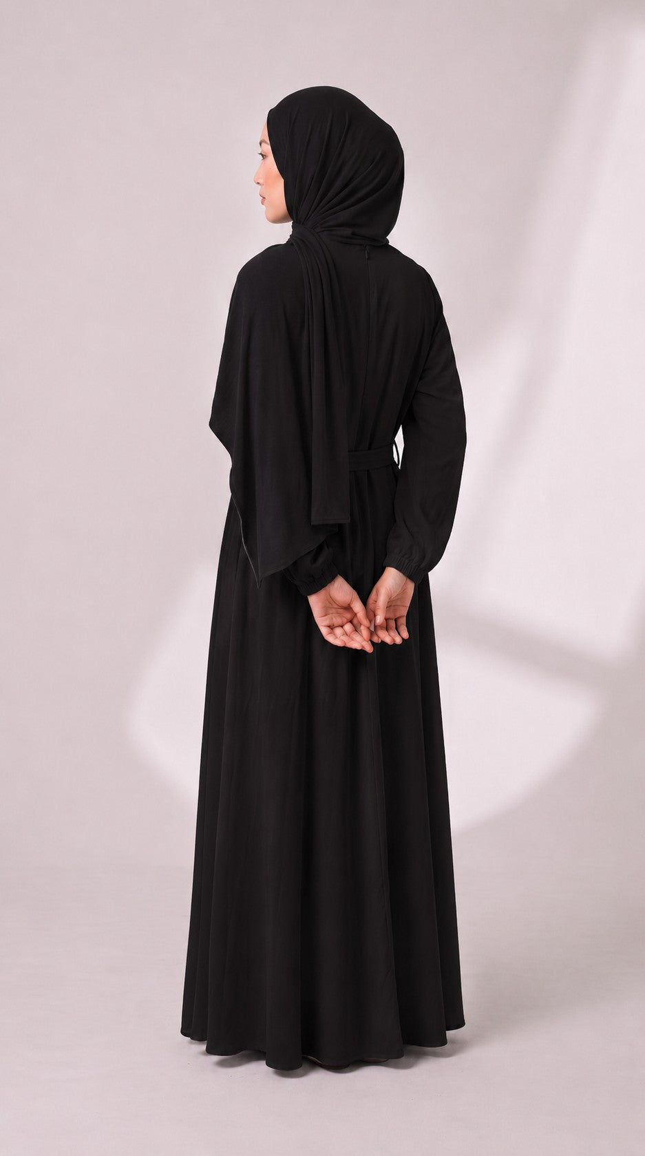 Model trägt ein schlichtes, schwarzes Eternal Aura Abaya-Kleid mit passendem Hijab in einer eleganten Rückenansicht.