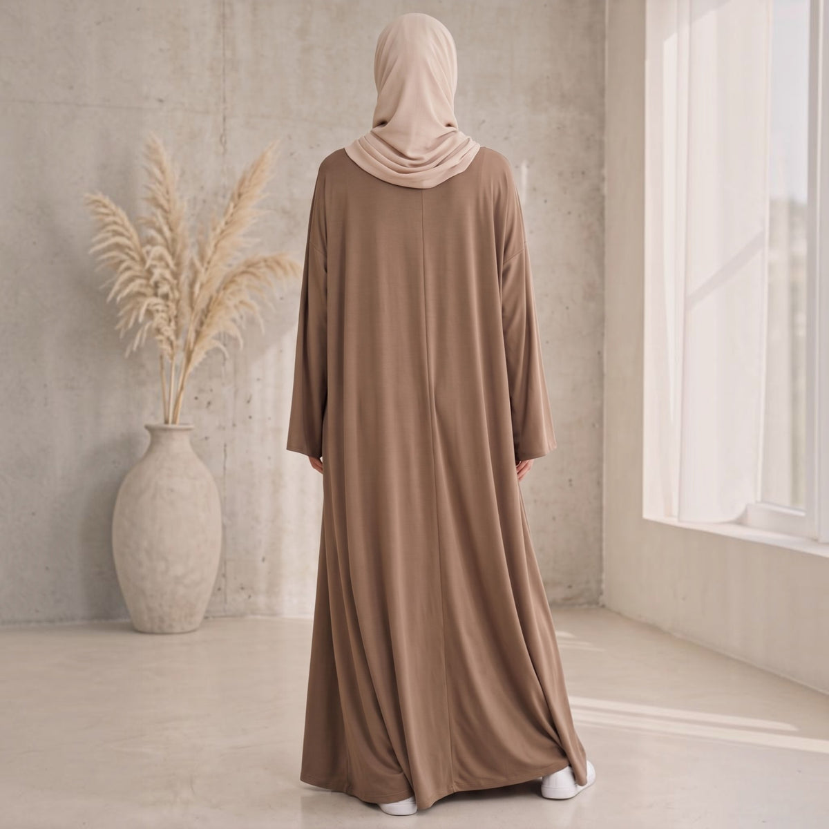 Eternal Aura The Serein Abaya in braun mit beigem Hijab, von hinten gesehen in einem minimalistischen Raum.