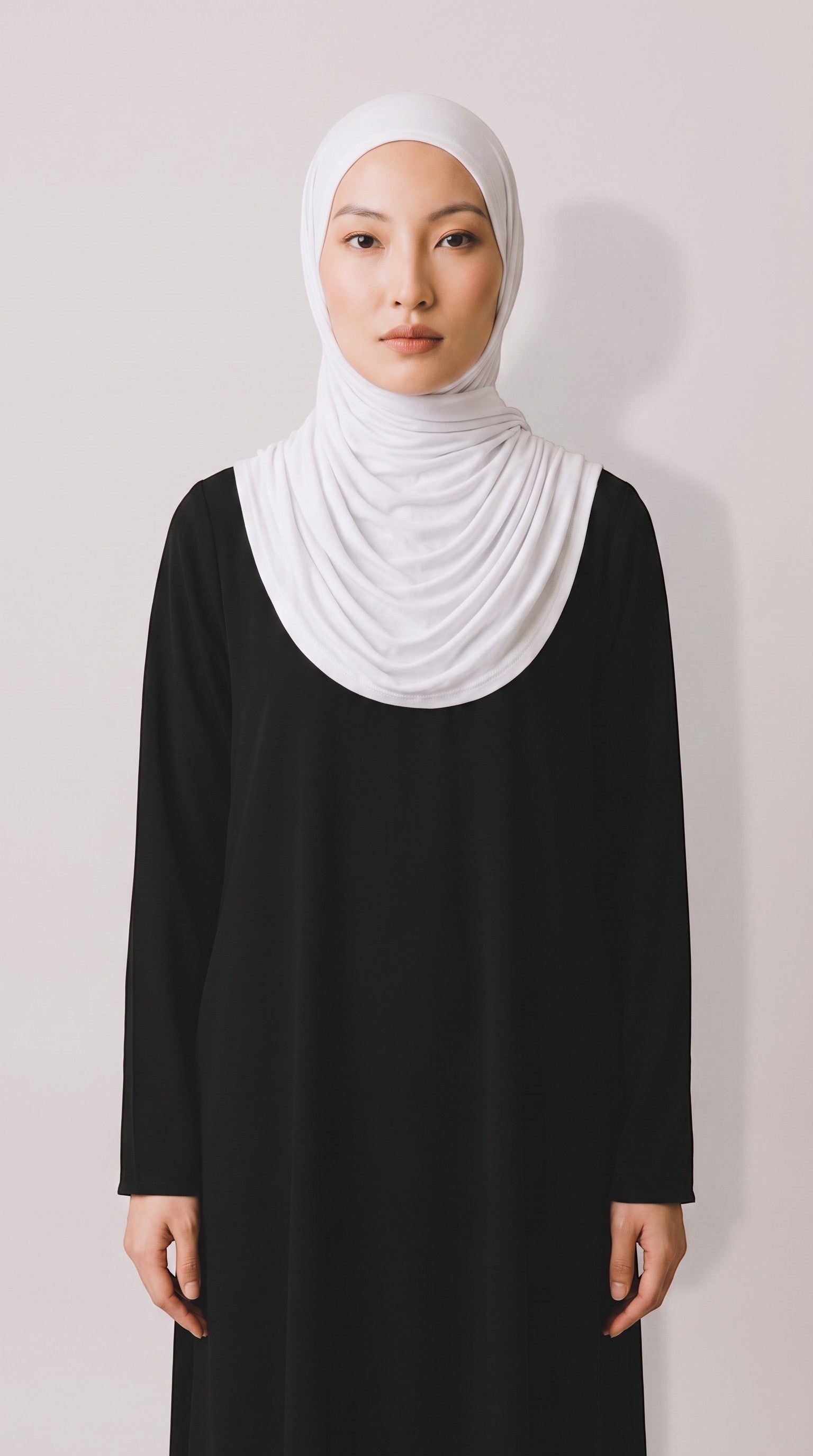 Model wearing a soft white Eternal Aura jersey hijab with a black long-sleeved dress against a neutral background